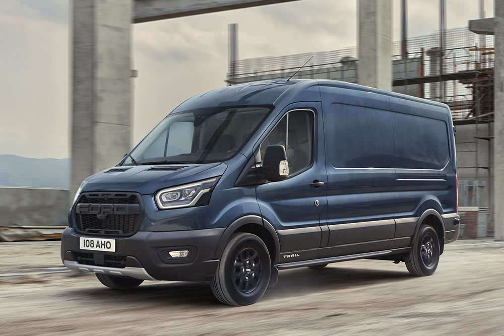 Ford Transit varebil med valgfri Trail-pakke som kjører på en industriell eiendom.