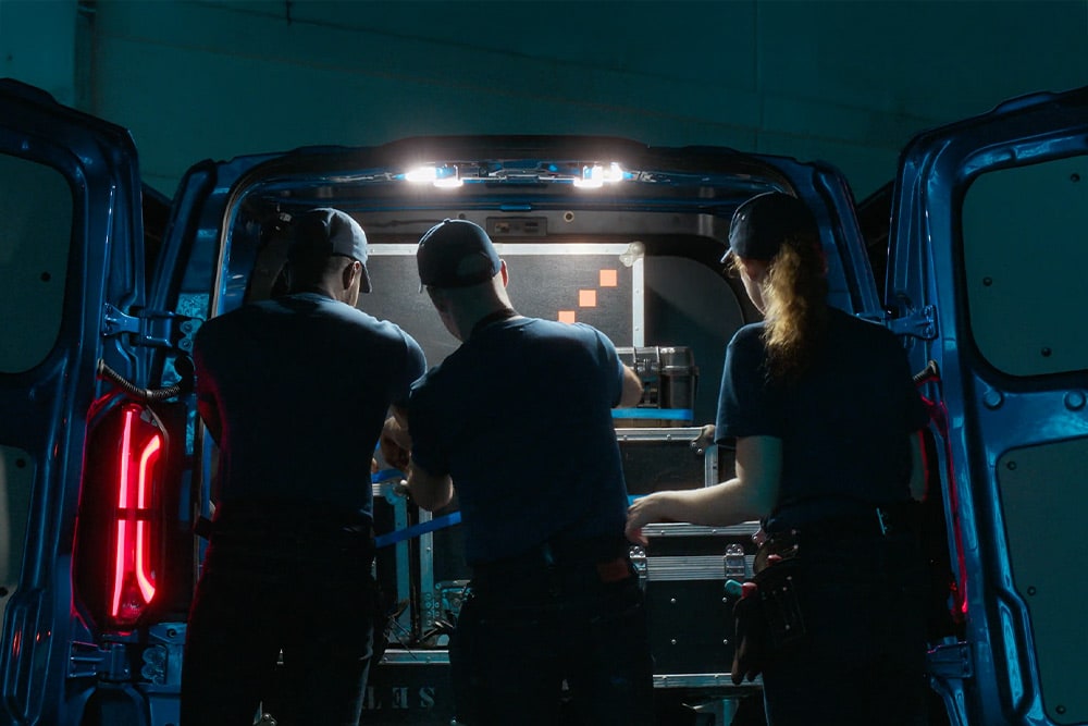 Tre personer som jobber bak i en Ford Transit Custom-varebil.