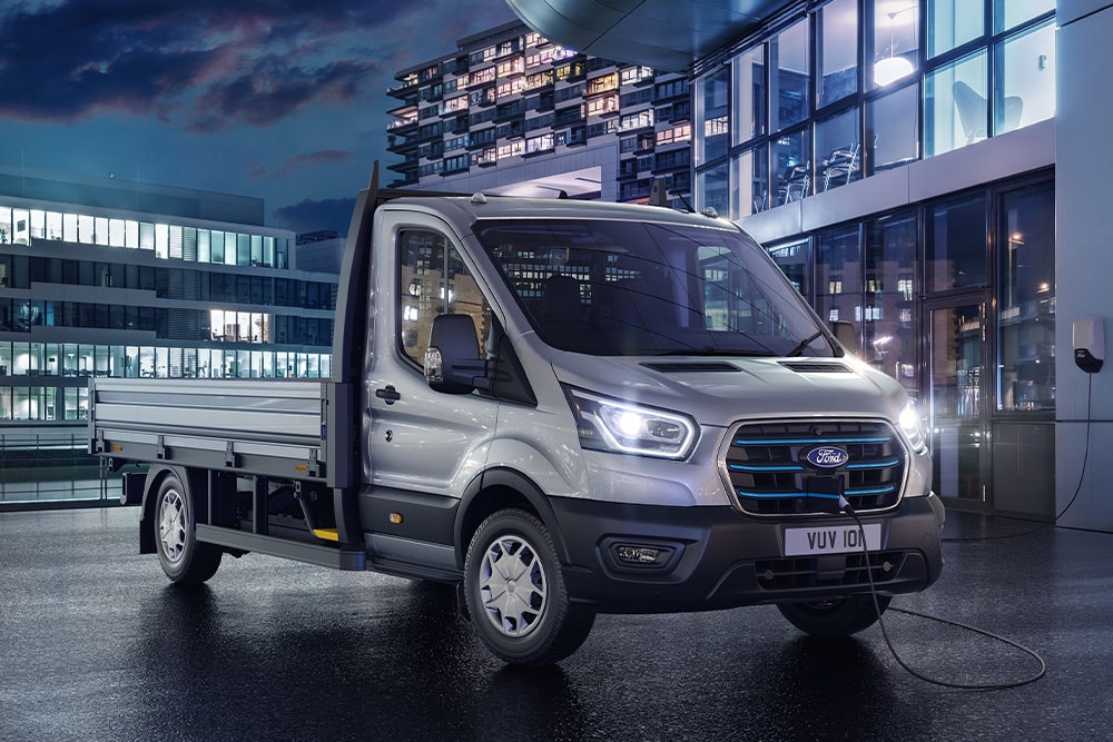 Sølvfarget Ford Transit Chassis Cab parkert foran en moderne bygning om natten.