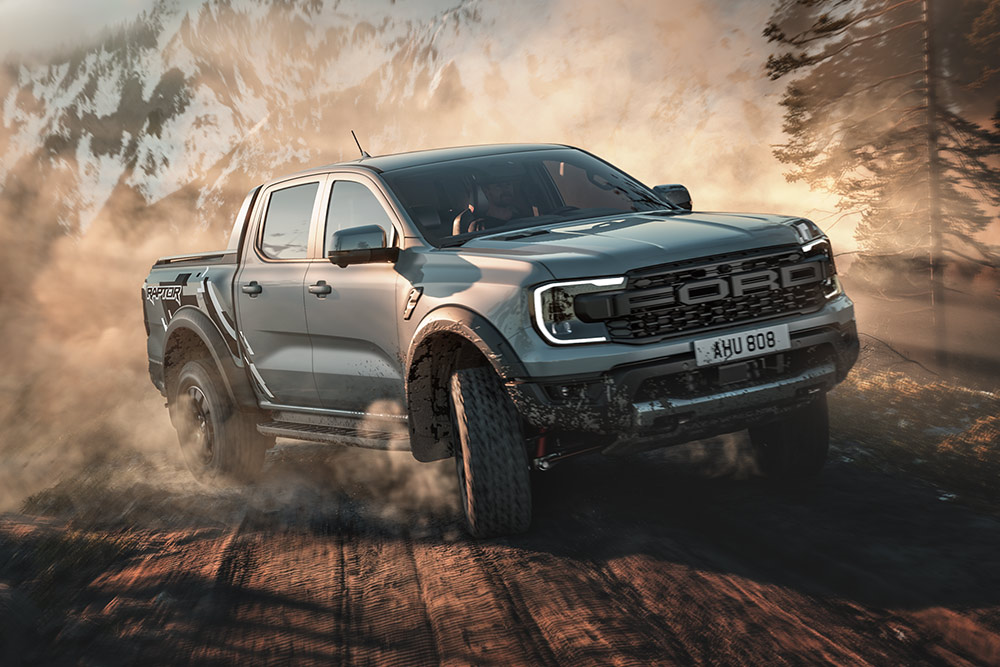 Ford Ranger Raptor i Baja som kjører på en grusvei med fjellandskap i bakgrunnen.